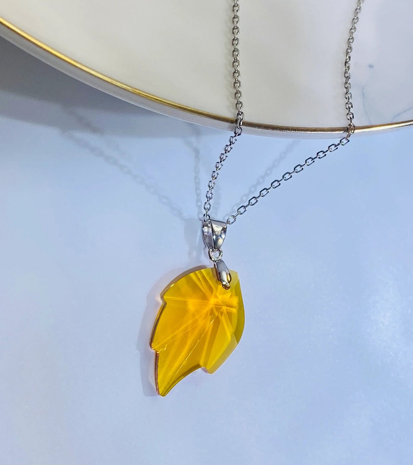 Introduce this vibrant yellow crystal maple leaf pendant to your collection, inspired by popular European designs. Crafted from 925 sterling silver, this piece captures the intricate detail of a maple leaf with a brilliant yellow crystal centerpiece, offering a stylish and seasonal look. A high-demand item perfect for wholesale buyers looking for accessible luxury and current fashion trends.