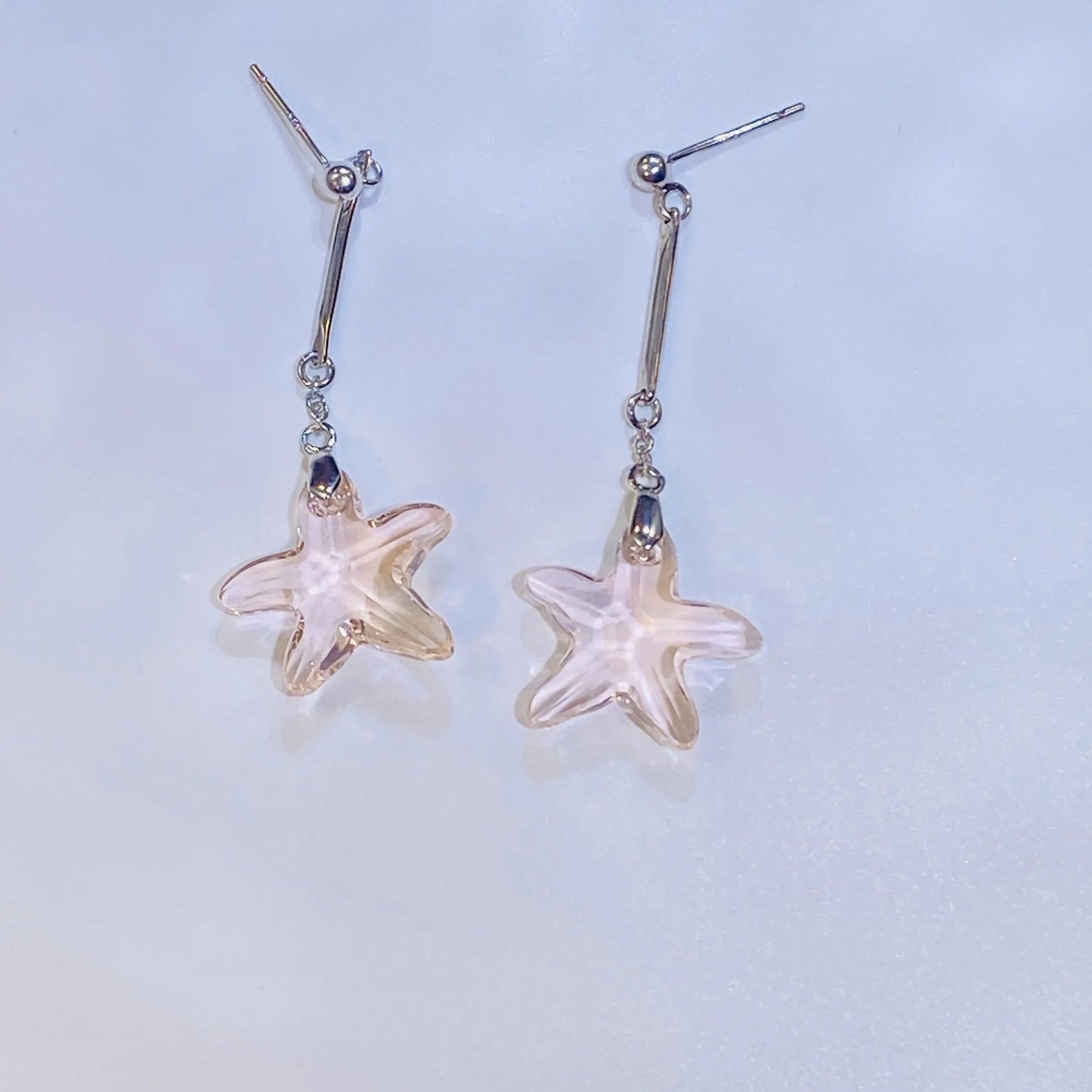 Source these stunning pink crystal starfish earrings for your inventory. The central crystal, in a flattering cherry blossom hue, provides exceptional sparkle, comparable to leading crystal brands. Set in high-grade 925 sterling silver, the unique, coastal-inspired design is both playful and elegant. Ideal for wholesale clients seeking unique, high-quality silver jewelry with strong market appeal.