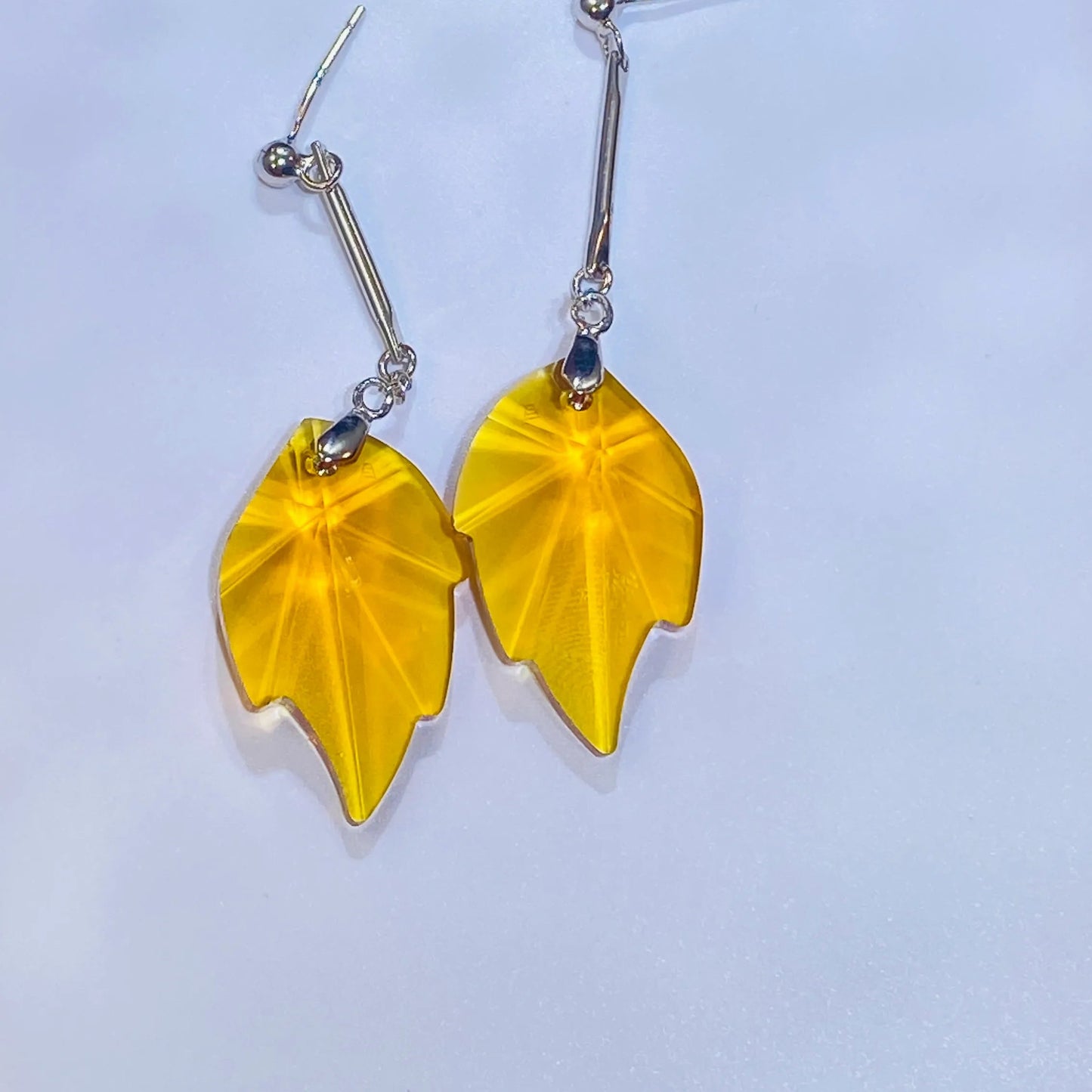 Source these stunning maple leaf earrings, showcasing a brilliant yellow crystal with a sparkle comparable to top crystal brands. The design is set in durable 925 sterling silver. These fashionable dangle earrings provide a luxurious, accessible option for wholesale clients targeting the Western fashion market.
