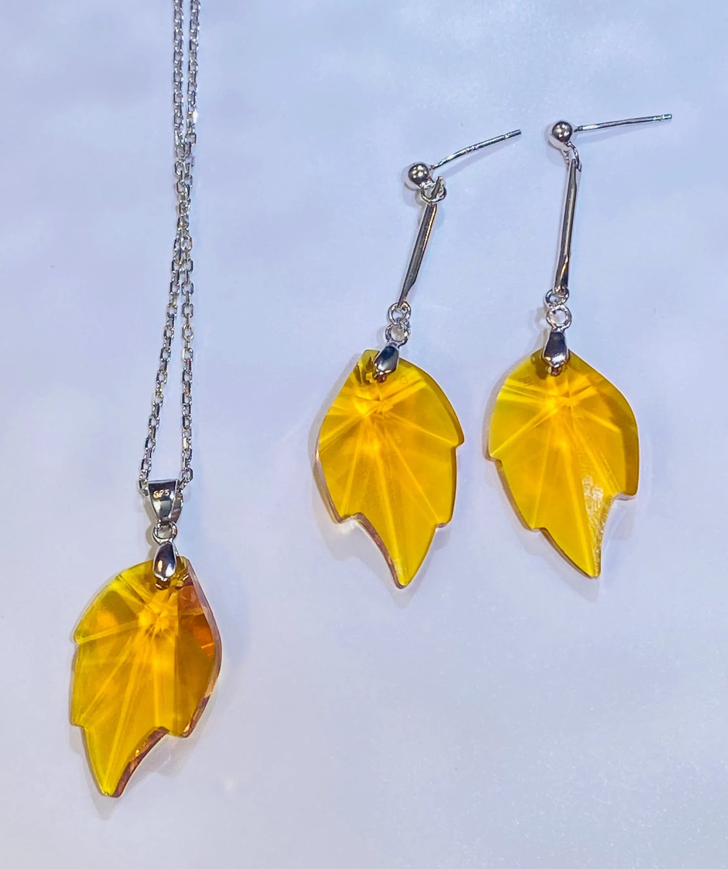 Source these stunning maple leaf earrings, showcasing a brilliant yellow crystal with a sparkle comparable to top crystal brands. The design is set in durable 925 sterling silver. These fashionable dangle earrings provide a luxurious, accessible option for wholesale clients targeting the Western fashion market.