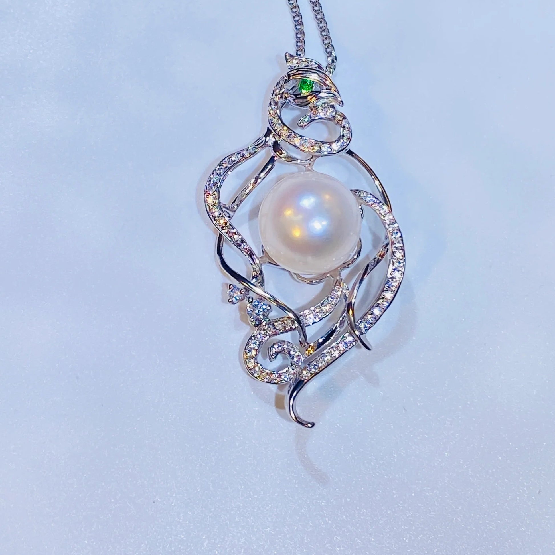 Embrace a piece with a story. Our stunning phoenix necklace draws inspiration from ancient Chinese culture, representing a woman's free-spirited and elegant nature. Made with fine gold-plated silver, the detailed phoenix design features a captivating green zircon eye and is adorned with genuine freshwater pearls. It's a truly creative and distinctive accessory that stands out from the crowd.