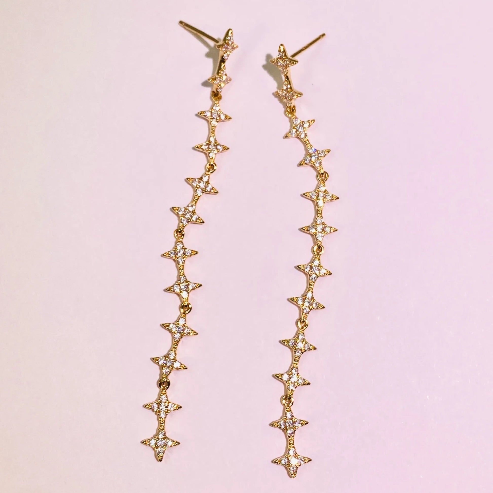 These exquisite, long star chain dangle earrings are crafted with 5A grade imported zircon and feature a thick 1.0um champagne gold plating. Our advanced silver-to-K gold plating process achieves the luxury look and feel of fine gold jewelry, perfect for discerning B2B buyers seeking high-quality, fashion-forward pieces.